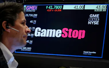 ゲームストップの取引情報とニューヨーク証券取引所のトレーダー(写真は2024年5月)=ロイター