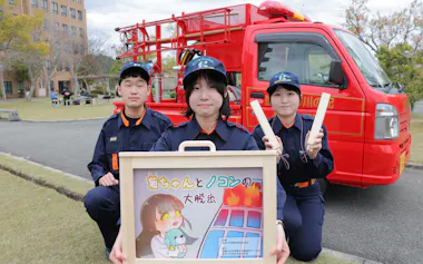 紙芝居を手にする学生消防団の坂星那さん㊥ら