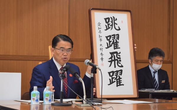 大村秀章知事は直筆の書を掲げて予算案の狙いを説明した（17日、愛知県庁）