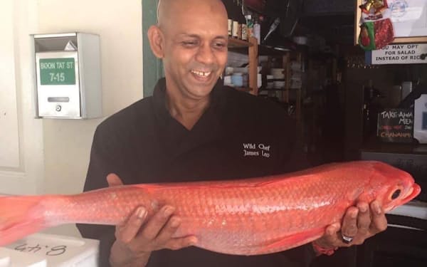 沖縄から届いた高級魚を手に笑顔を見せるシンガポールの飲食店のシェフ