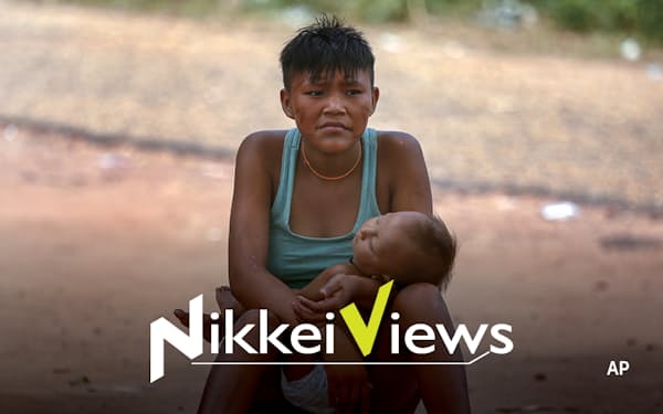 子どもを抱え、保健施設の外に座るヤノマミ族の女性（２月、ブラジル北部ロライマ州）＝ＡＰ
