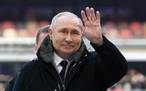 22日、モスクワの競技場「ルジニキ・スタジアム」に到着し、大規模集会の参加者に手を振るロシアのプーチン大統領＝AP