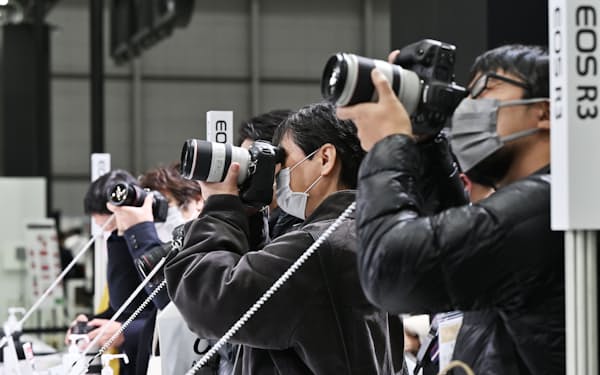 キヤノン製のカメラを試す人たち(23日、横浜市)