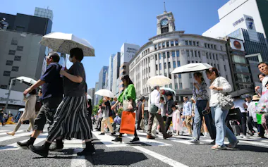 強い日差しの中、日傘を差して歩く人たち(17日、東京・銀座)