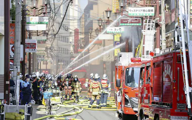 大阪市中央区の火災現場で消火活動をする消防隊員ら(18日午前)=共同