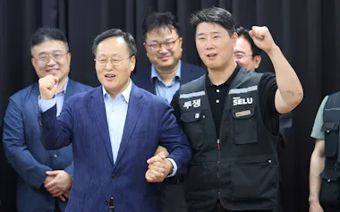 暫定合意を発表したサムスン電子の人事担当役員㊧と労働組合の崔委員長(20日、韓国・水原市)=聯合