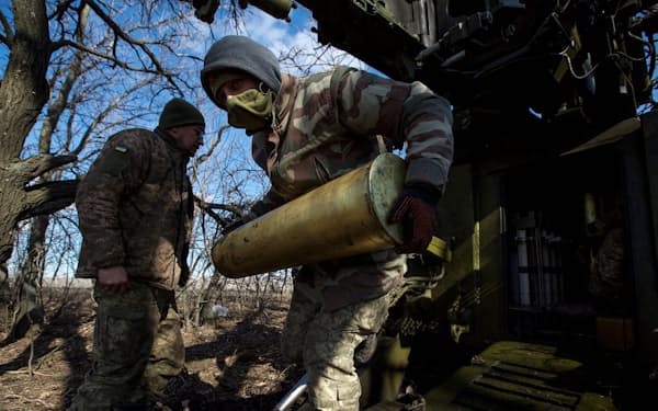 ロシア軍が攻撃するなか、自走式榴弾（りゅうだん）砲の砲弾を運ぶウクライナ軍兵士（5日、バフムト近郊）=ロイター