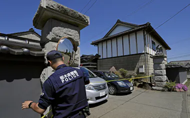 強盗殺人事件現場の住宅に規制線を張る警察官=17日午前9時52分、栃木県上三川町