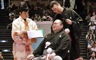 断髪式で先代師匠の宮城野親方㊨から大銀杏に最後のはさみを入れられた元関脇宝富士の桐山親方(31日、両国国技館)=共同