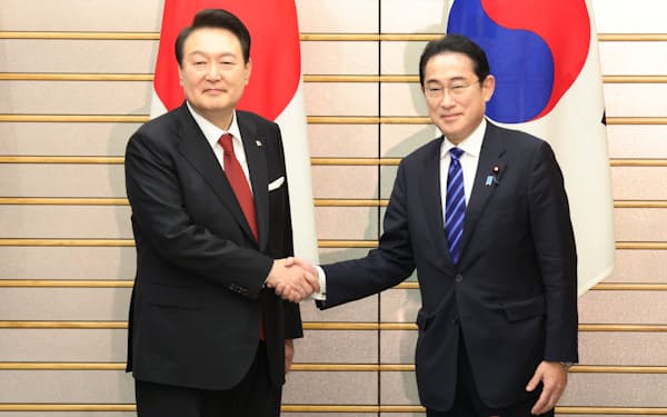 首脳会談を前に韓国の尹錫悦大統領㊧と握手する岸田首相（16日、首相官邸）