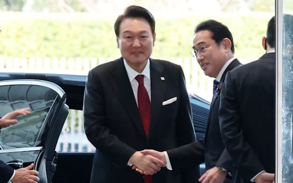 首相官邸に到着した韓国の尹錫悦大統領（左）を握手で出迎える岸田首相（16日、首相官邸）