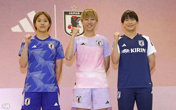 サッカー女子W杯で日本代表が着用するアウェー用の新ユニホームを着てポーズをとる、植木理子(中央)。左はホーム用ユニホーム姿の小林里歌子、右は藤野あおば(23日、東京・国立競技場)=共同