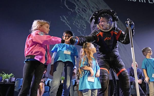 アクシオム・スペースの新しい宇宙服を着た技術者（右）と、発表会に参加した子どもたち（米テキサス州）＝AP