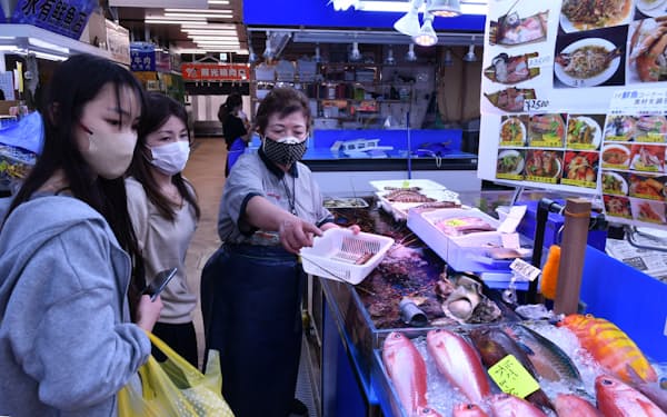 長嶺次江さんは観光客に食材の調理法を優しくアドバイス（3月28日、那覇市）