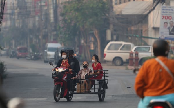 大気汚染でかすむ市内をマスクをして移動する人たち（9日、タイ・チェンマイ）＝小林健撮影