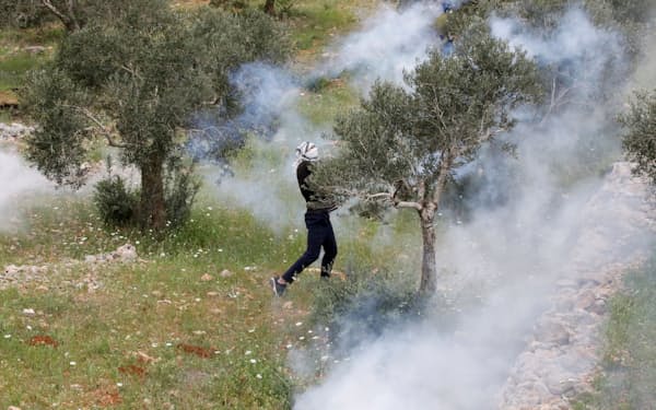 イスラエル軍が発射した催涙ガスに反応するパレスチナのデモ参加者（10日、ナブルス近郊）＝ロイター