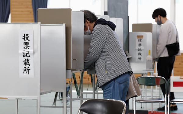 参院大分選挙区補欠選挙の投票所で、投票用紙に記入する有権者（23日午前、大分市）=共同