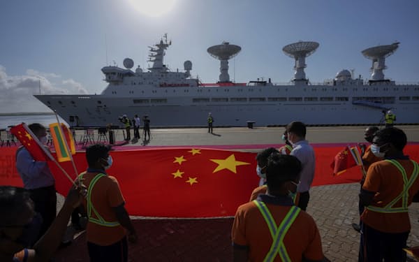 FILE - Sri Lankan port workers hold a Chinese national flag to welcome Chinese research ship Yuan Wang 5 as it arrives in Hambantota International Port in Hambantota, Sri Lanka, Tuesday, Aug. 16, 2022. A Chinese scientific ship bristling with surveillance equipment docked in a Sri Lankan port. Hundreds of fishing boats anchored for months at a time among disputed islands in the South China Sea. And ocean-going ferries, built to be capable of carrying heavy vehicles and large loads of people. (AP Photo/Eranga Jayawardena, File)