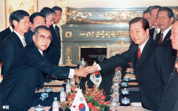 1998年10月、日韓首脳会談の全体会合で握手する小渕首相㊧と韓国の金大中大統領(東京・元赤坂の迎賓館)