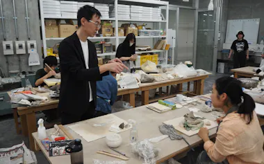 共通工房の陶磁成形室で、学生の制作をサポートする技術専門員の今西氏(左手前)