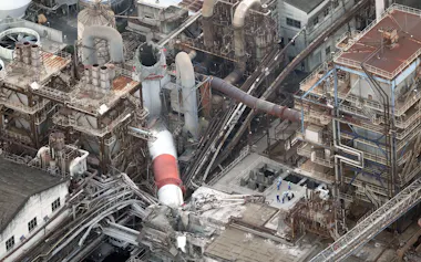 地震の影響で折れた日本製紙の八代工場の煙突(28日午後7時5分、熊本県八代市)=共同通信社ヘリから