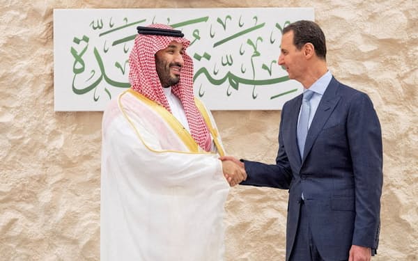 19日のアラブ首脳会議で、サウジアラビアのムハンマド皇太子㊧と握手するシリアのアサド大統領＝ロイター