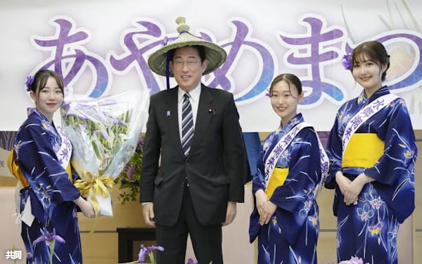 茨城県潮来市の「あやめ娘」から贈呈された「あやめがさ」をかぶる岸田首相(29日午後、首相官邸)=共同