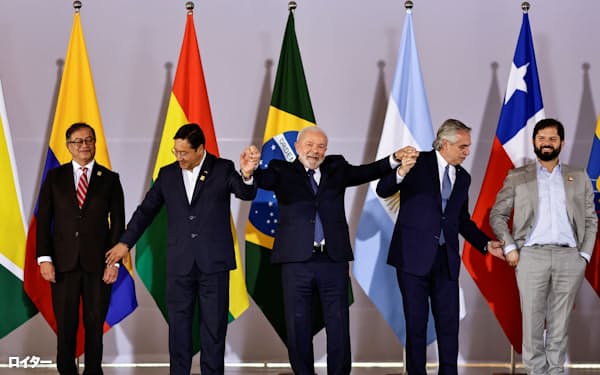 手をつなぐブラジルのルラ大統領㊥ら南米首脳(30日、ブラジリア)=ロイター