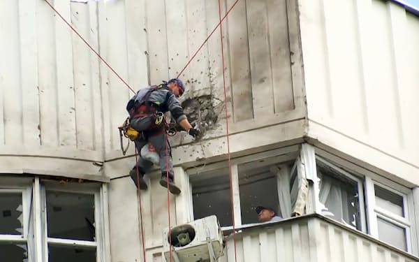 30日のモスクワ市内へのドローン攻撃によるビルの損傷を調べる捜査官ら=AP