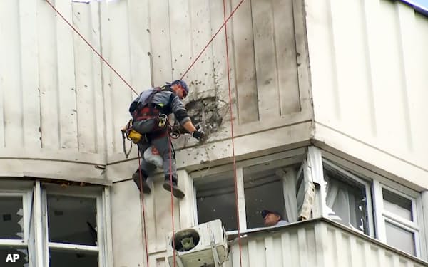 30日のモスクワ市内へのドローン攻撃によるビルの損傷を調べる捜査官ら=AP