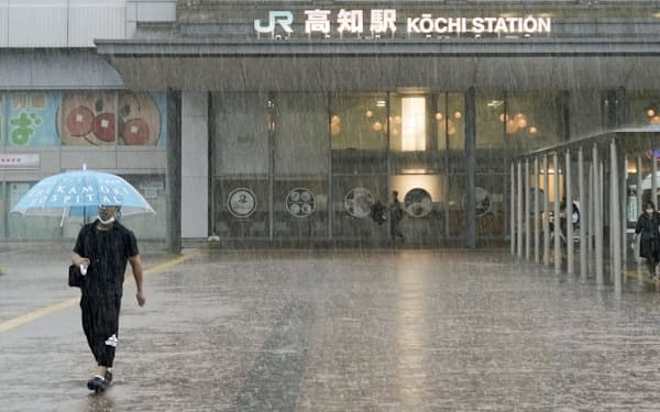 JR高知駅前で、強い雨の中を歩く人（2日午前）=共同