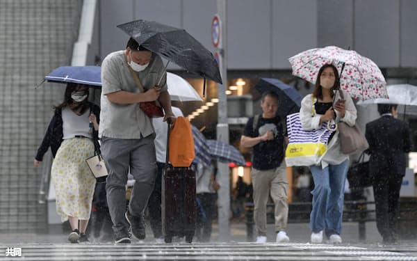 強い雨が降る名古屋駅前を傘を差して歩く人たち(2日午後、名古屋市)=共同