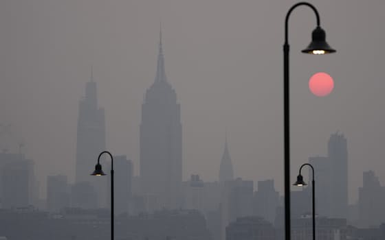 カナダの山火事の影響でかすんで朝日が赤く染まった米ニューヨーク市の空（7日）=AP
