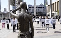 韓国人元徴用工を象徴する像の前で、韓国の尹錫悦大統領の対日外交を批判する人たち（3月、ソウル）＝共同