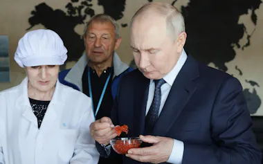 北方領土・択捉島の魚加工施設を訪れ、食品を味見するロシアのプーチン大統領㊨(13日)=AP