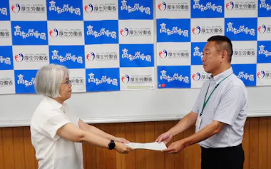 高知地方最低賃金審議会の大井方子専門部会長㊧から答申を受け取る高知労働局の中原慎一労働基準部長(28日)