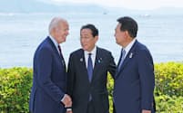 記念撮影を終えバイデン米大統領（左）、韓国の尹錫悦大統領（右）と話す岸田首相（21日、広島市）