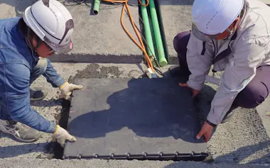 送電コイルなどで構成する給電ユニットを道路に埋設する様子。大成建設の動画から日経クロステックがキャプチャー(写真:大成建設)