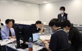 IIJのセキュリティ教習所でチューターを務めるIIJ社員（右奥）と実習をする受講者（7月、東京都千代田区）