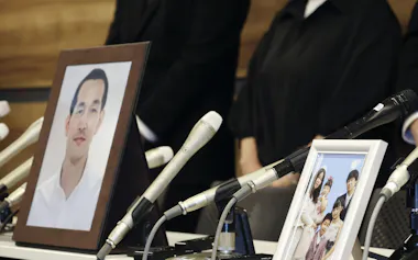 遺族の記者会見の席に置かれた松本幸司さん一家と高峰啓三さんの写真(20日午後、津市)=共同