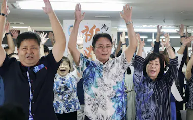 再選を確実にし支援者と喜ぶ知念覚氏(中央、25日)=共同