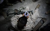 2006年、イラクのアルファルージャで、軍用の金属探知機を膝に乗せ、テトリスをプレイする米海兵隊の兵士。（PHOTOGRAPH BY TOBY MORRIS, ZUMA PRESS/ALAMY STOCK PHOTO）