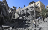 空爆で破壊された建物を調べる住民（15日、ガザ）＝AP
