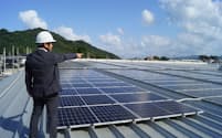 スーパーの屋上に設置した太陽光発電設備について説明するごうぎんエナジーの社員