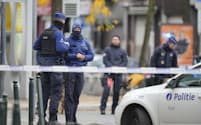 17日、ブリュッセルの銃撃事件の容疑者が死亡したとみられる現場近くに集まる警察官＝AP