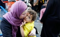20日、パレスチナの家を逃れ、国連の運営する施設に避難した女性と子供=ロイター
