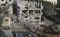 イスラエル軍の空爆で破壊された建物で生存者を探す人々（22日、ガザ南部）＝AP