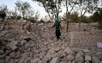 アフガニスタンのヘラート州ジンダジャン地区のスィア・アーブ村で、地震前に自宅があった辺りを歩く男性。アフガニスタンでは10月に入ってから同じ規模の大地震が4回立て続けに発生しており、村はそのうちの1つの被害を受けた。（PHOTOGRAPH BY LYNSEY ADDARIO, NATIONAL GEOGRAPHIC）