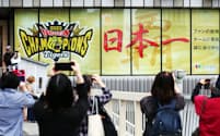 阪神タイガースが日本一となり、百貨店のディスプレーを写真に収める人たち（6日午前、大阪市北区の阪神梅田本店）