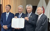和歌山県庁で署名した協定書を示す岸本周平知事㊧、トーヨーカネツの大和田能史社長（左から２人目）ら関係者（８日）
